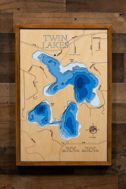 A precision laser-cut, multi-layered wooden map of North and South Twin Lakes in Itasca County, Minnesota, a connected pair of clear Northwoods lakes covering 418 combined acres alongside the city of Marble in the Iron Range. The natural wood top layer captures both shorelines and their connecting channel in fine detail, while a light-to-dark blue gradient conveys depths reaching 42 feet. A handcrafted statement piece for any Minnesota lake cabin, home, or outdoor enthusiast's wall.