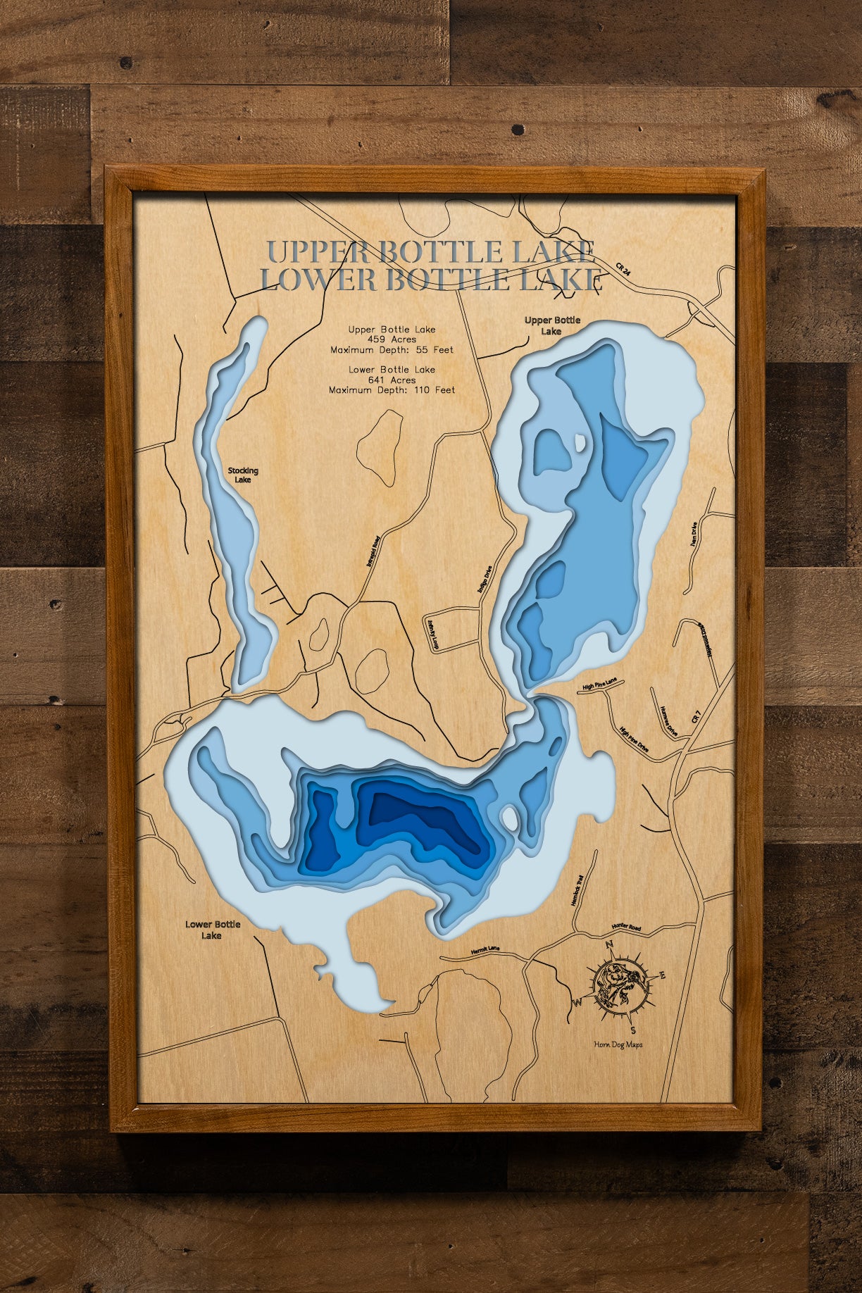 A meticulously crafted, laser-cut, multi-layered wooden map showcasing Upper and Lower Bottle Lakes in Hubbard County, Minnesota. The detailed topographic representation displays both connected lakes with their combined 1,100 acres, the narrow channel linking them, and 10 miles of intricate shoreline detail, with graduated blue layers illustrating depths from shallow areas to Lower Bottle's impressive 110-foot maximum.