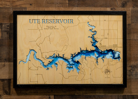 A framed wooden map of Ute Reservoir, Utah, featuring a natural wood grain background with etched land outlines and a blue 3D lake depth effect. The map is housed in a black frame and mounted on a rustic dark wood plank wall.