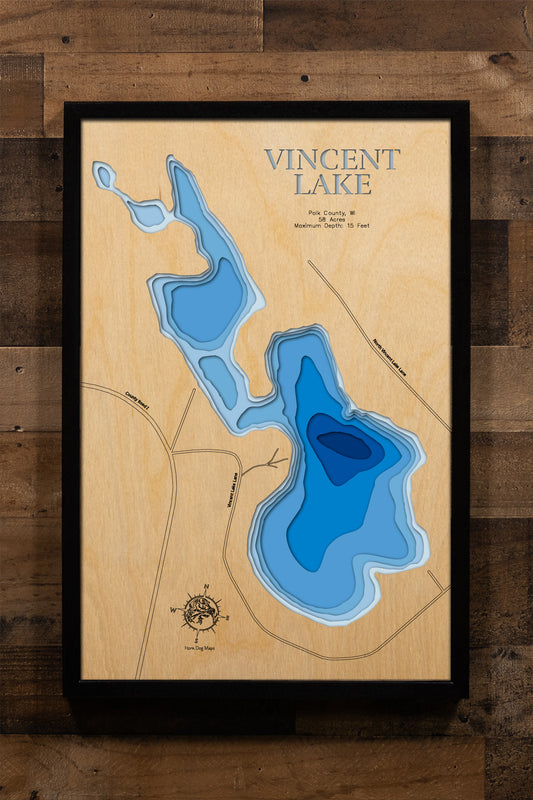 A detailed, laser-cut, multi-layered wooden map of Vincent Lake in Polk County, Wisconsin, showcasing the intimate 58-acre lake near Luck, Milltown, and Balsam Lake. The topographic design features natural wood layers highlighting the sandy bottom and surrounding countryside, with graduated blue water layers illustrating the shallow 15-foot maximum depth.
