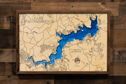 A highly detailed, laser-cut, and multi-layered wooden map of Lake Wallenpaupack, a large reservoir in Pike and Wayne Counties, Pennsylvania. The map shows the lake's distinct shape and its extensive 52-mile shoreline. The varying depths of the lake, reaching a maximum of 60 feet, are represented by different layers of wood.