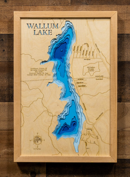 A framed 3D wooden depth map of Wallum Lake, featuring layered blue and cyan pools on a light natural wood background, mounted on a dark wood plank wall.