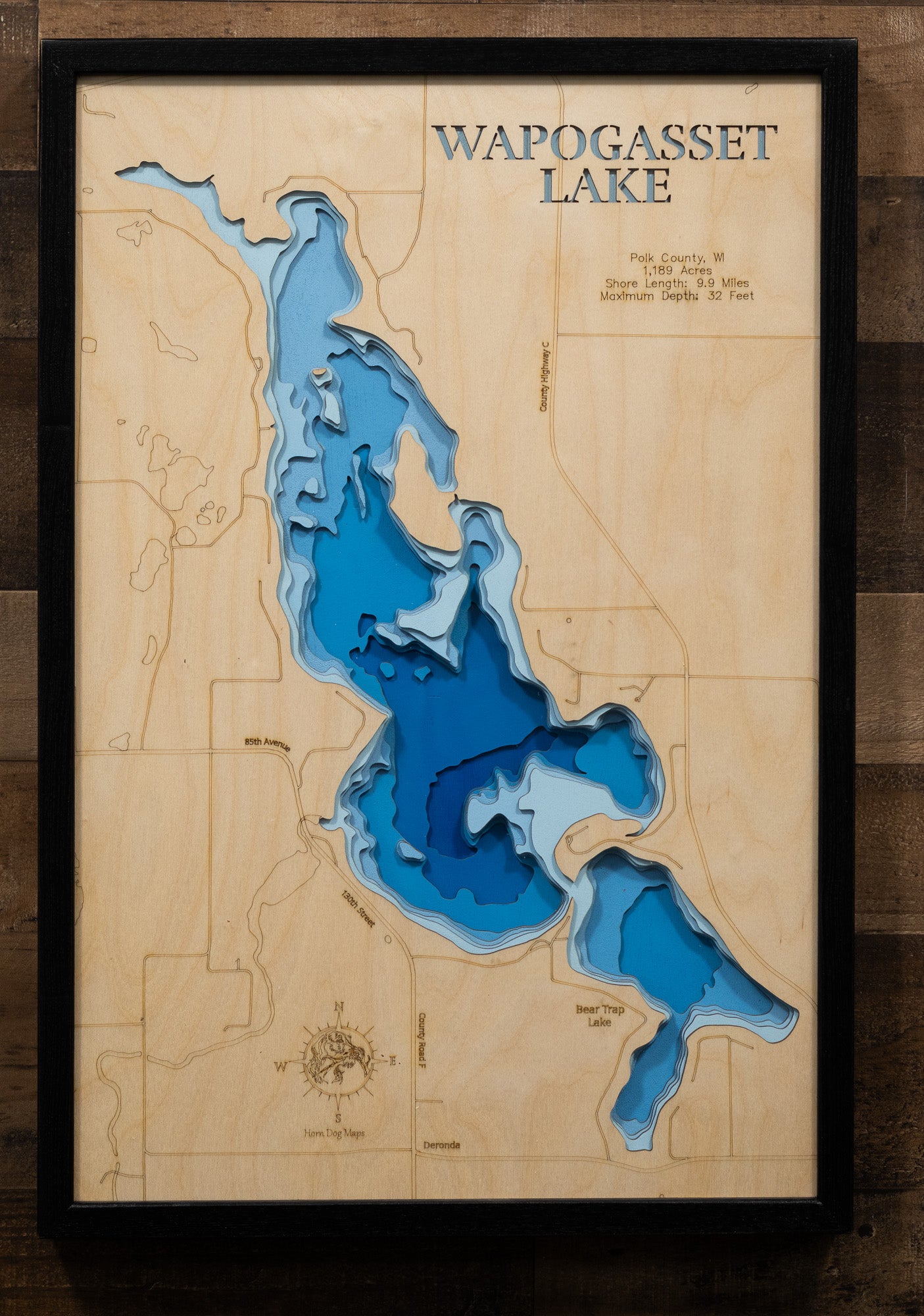 Wooden topographic map of Wapogasset Lake with blue water elevation details on a wooden background.