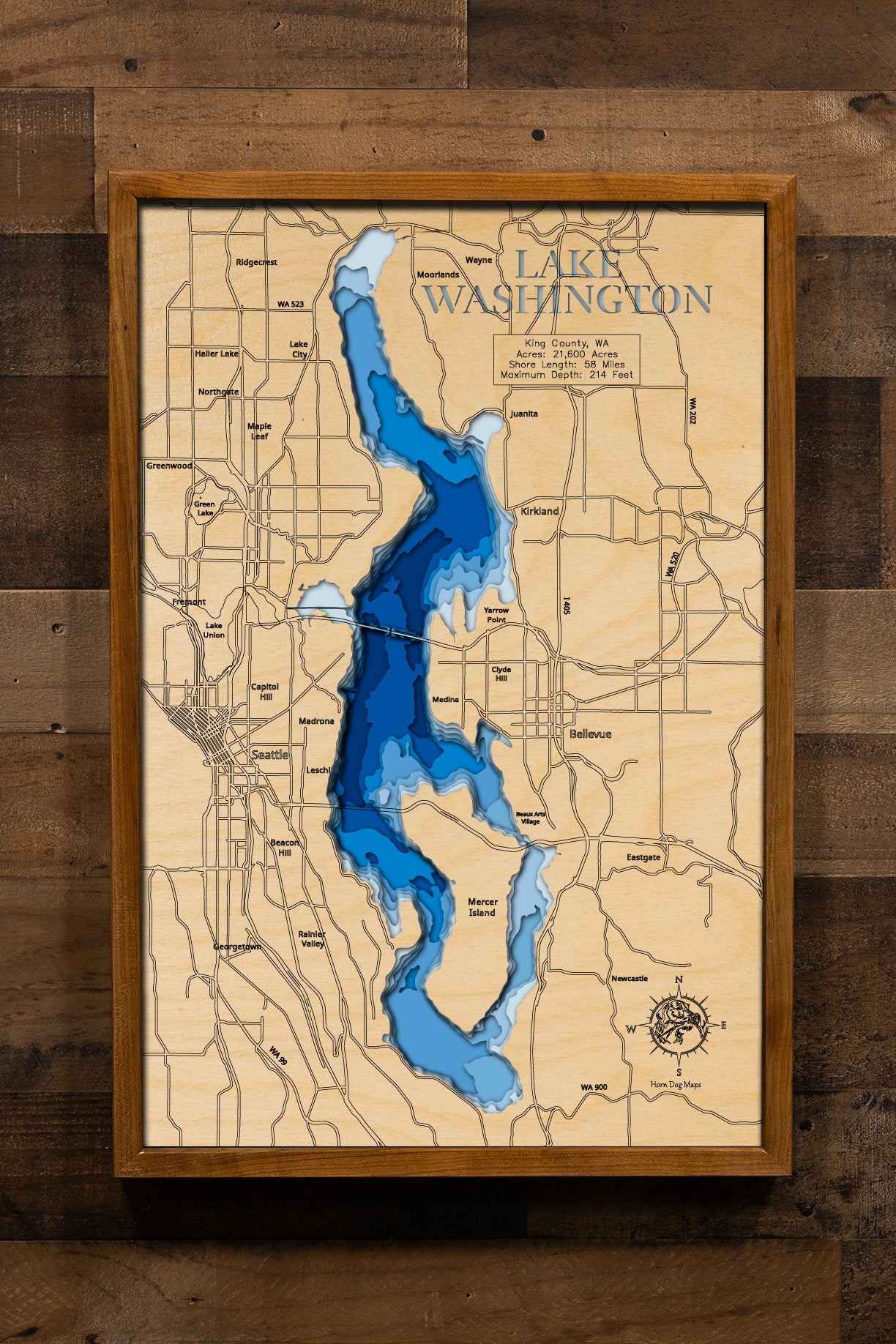 A highly detailed, 3D laser-cut wooden map of Lake Washington in King County, Washington. The multi-layered design uses different wood tones to illustrate the lake's bathymetric contours and deepest points. Etched details include the lake name, county lines, the floating bridges, and surrounding cities, creating a unique and intricate piece of art.