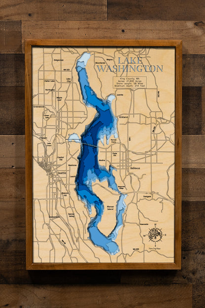 A highly detailed, 3D laser-cut wooden map of Lake Washington in King County, Washington. The multi-layered design uses different wood tones to illustrate the lake's bathymetric contours and deepest points. Etched details include the lake name, county lines, the floating bridges, and surrounding cities, creating a unique and intricate piece of art.