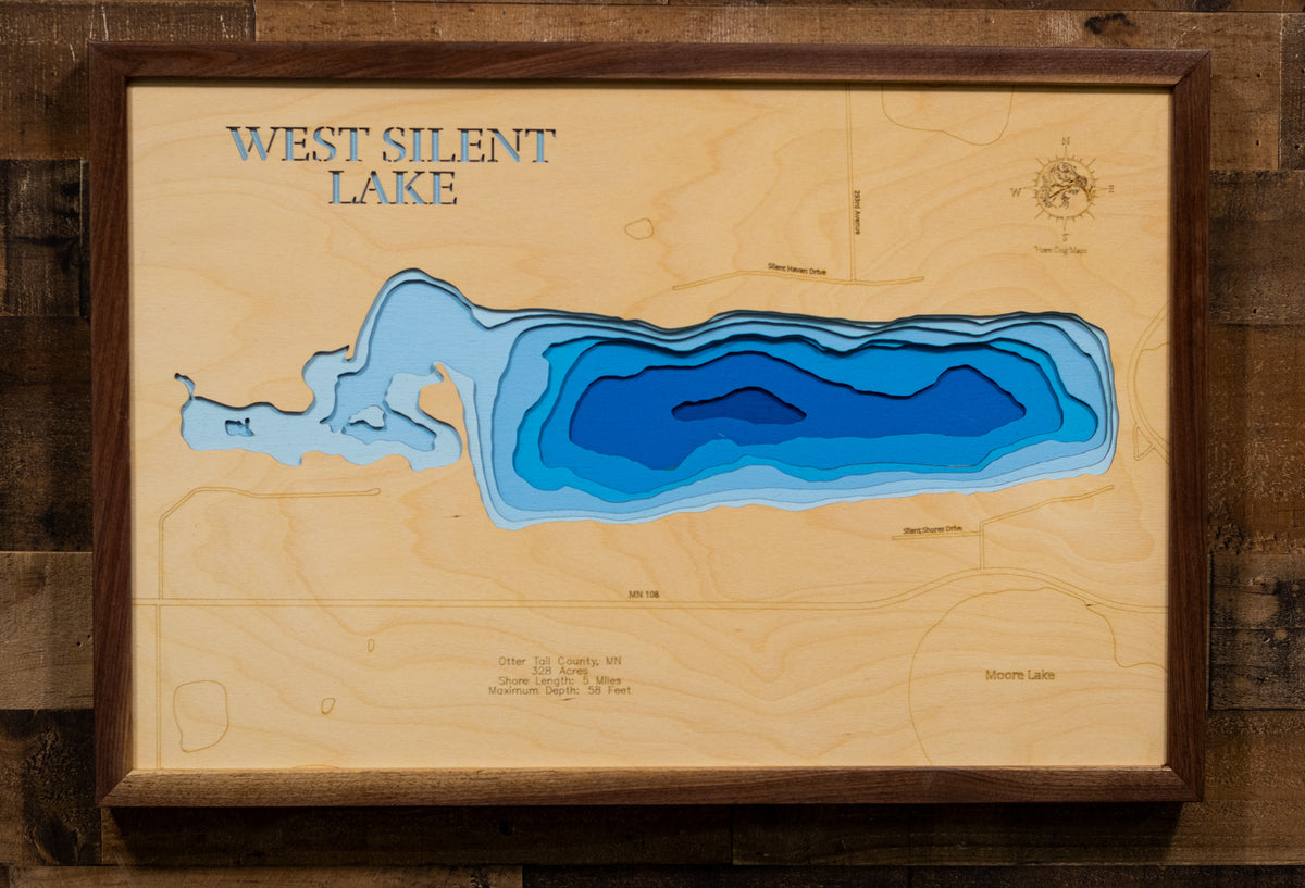 A precision laser-cut, multi-layered wooden map of West Silent Lake in Otter Tail County, Minnesota, near Dent and Pelican Rapids in Minnesota's lake country. The natural wood top layer captures 5 miles of shoreline in fine detail, while a light-to-dark blue gradient conveys the lake's impressive 58-foot depth. A handcrafted statement piece for any Minnesota lake cabin, home, or outdoor enthusiast's wall.