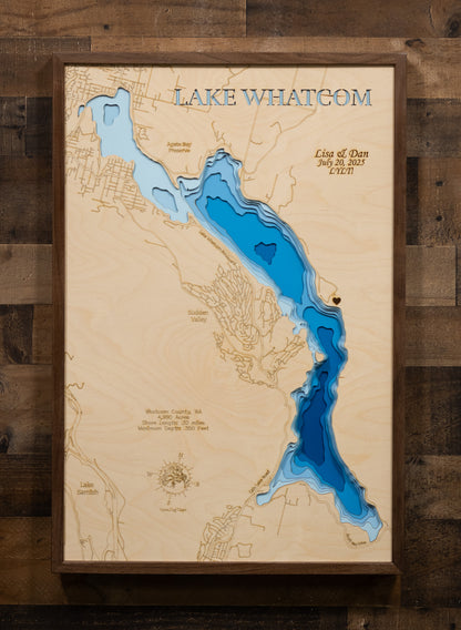 A detailed, laser-cut topographic map of Lake Whatcom, Washington, highlighting its three distinct basins and the extreme maximum depth of 350 feet. The design emphasizes the narrow, 10-mile length of the lake and includes a key point for the City of Bellingham's drinking water intake in the middle basin.