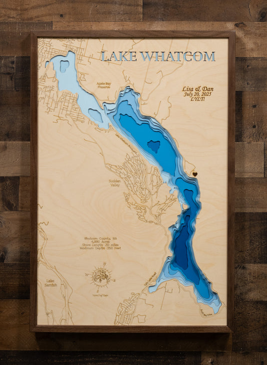 A detailed, laser-cut topographic map of Lake Whatcom, Washington, highlighting its three distinct basins and the extreme maximum depth of 350 feet. The design emphasizes the narrow, 10-mile length of the lake and includes a key point for the City of Bellingham's drinking water intake in the middle basin.