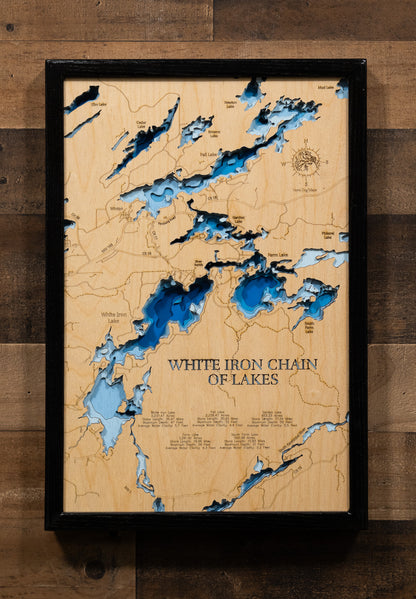 A laser-cut, layered wooden map of the White Iron Chain of Lakes in St. Louis County, Minnesota. The distinct shapes of White Iron, Garden, Farm, and South Farm Lakes, and their interconnected channels, are clearly visible within the forested landscape of northeastern Minnesota. The varying depths of the lakes, reaching a maximum of 56 feet, are represented by different layers of wood, illustrating their impressive underwater topographies.