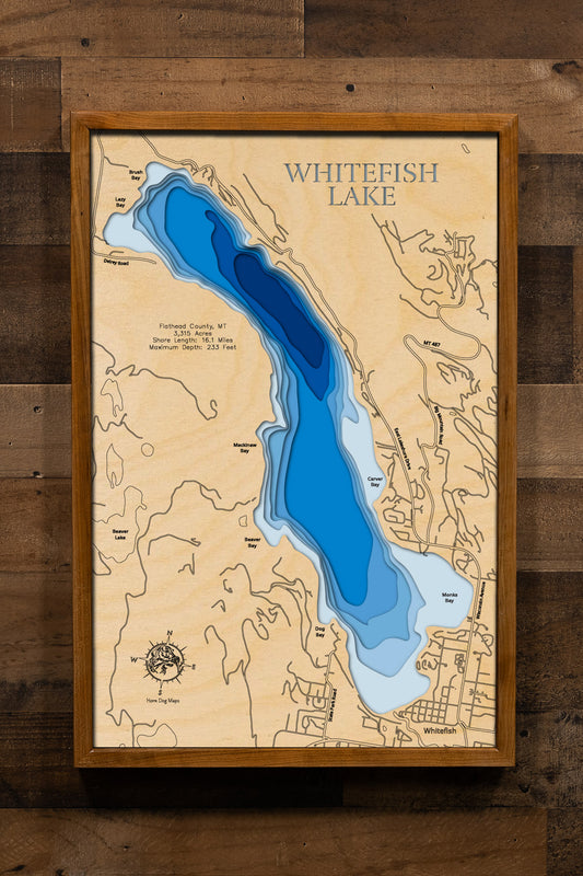 A highly detailed, laser-cut, and multi-layered wooden map of Whitefish Lake, a natural lake in Flathead County, Montana. The map shows the lake's distinct shape and its extensive 16.1-mile shoreline. The varying depths of the lake, reaching a remarkable 233 feet, are represented by different layers of wood.