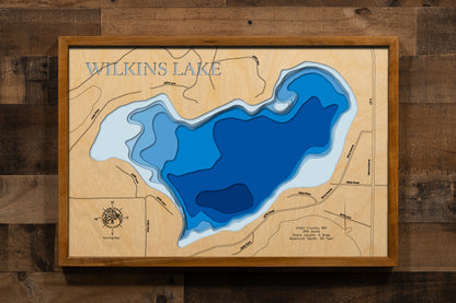 A detailed, laser-cut, multi-layered wooden map of Wilkins Lake in Aitkin County, Minnesota, showcasing the 349-acre lake with 4 miles of shoreline near Palisade and McGregor in the Big Sandy Lakes region. The topographic design features natural wood layers highlighting the forest-covered rolling hills and graduated blue water layers illustrating depths to the 39-foot maximum.