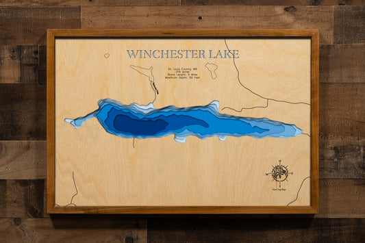 A precisely crafted, multi-layered laser-cut wooden topographic map of Winchester Lake in St. Louis County, Minnesota, illustrating the 319-acre wilderness basin with depth contours showing the 50-foot maximum depth, the five miles of rugged, heavily forested Canadian Shield shoreline with steep drop-offs, the carry-in boat access point, surrounding pristine boreal forest, and the tannin-stained waters characteristic of northeastern Minnesota's remote shield lakes.