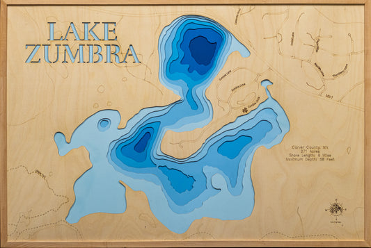 A meticulously detailed, laser-cut, multi-layered wooden topographical map of Lake Zumbra in Carver County, Minnesota, showcasing the 271-acre lake within Carver Park Reserve with depth contours from the 14-foot average to the 58-foot maximum depth. The natural wood top layer frames six miles of mostly undeveloped shoreline protected by Three Rivers Park District near Victoria, while graduated blue layers create a striking visual depth gradient across this premier Northern Pike fishery.